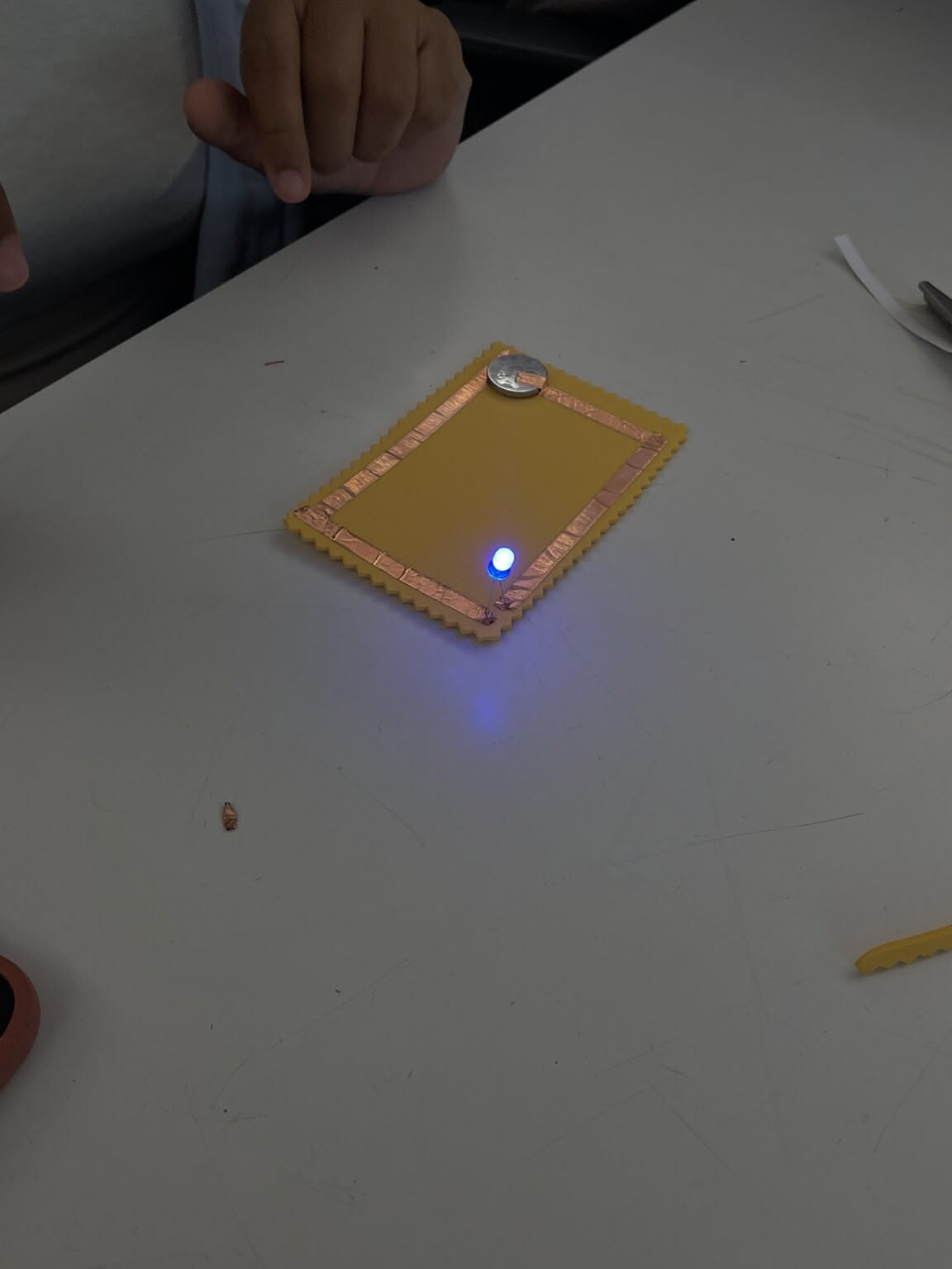 close-up of a single soft circuit board with an LED lit up
